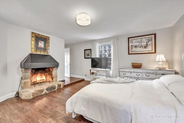 bedroom featuring a fireplace, baseboards, and wood finished floors