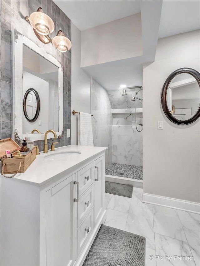 full bathroom featuring marble finish floor, a marble finish shower, vanity, and baseboards