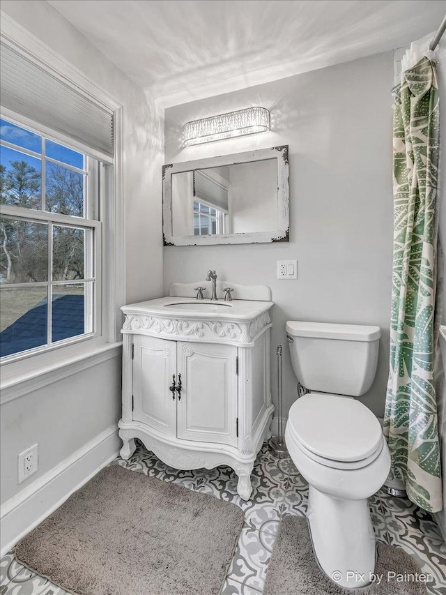 bathroom with baseboards, vanity, and toilet