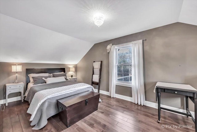 bedroom with vaulted ceiling, wood finished floors, and baseboards