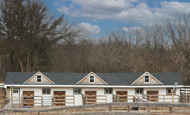 view of front of home featuring a shingled roof, an outbuilding, and an exterior structure