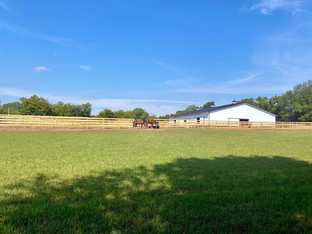 view of yard with an enclosed area, a rural view, and fence