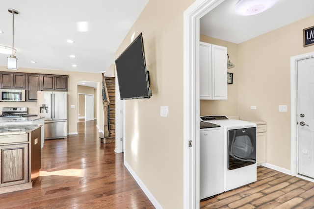 laundry area with cabinets, washing machine and dryer, and wood-type flooring