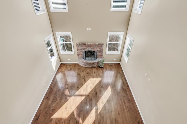 unfurnished living room featuring a high ceiling, a fireplace, and hardwood / wood-style flooring