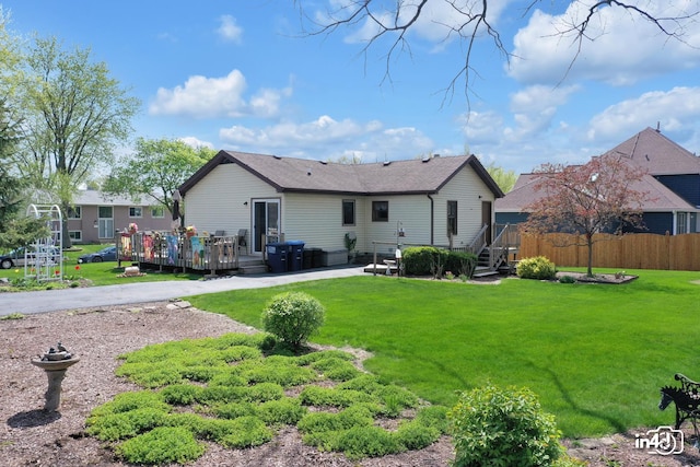 rear view of house featuring a lawn and a wooden deck