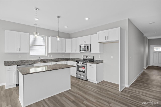 kitchen featuring pendant lighting, stainless steel appliances, a kitchen island, white cabinetry, and sink