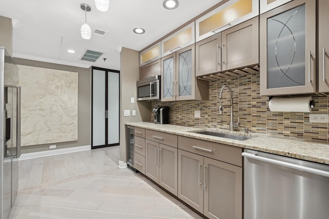 kitchen with light stone counters, stainless steel appliances, decorative light fixtures, and sink