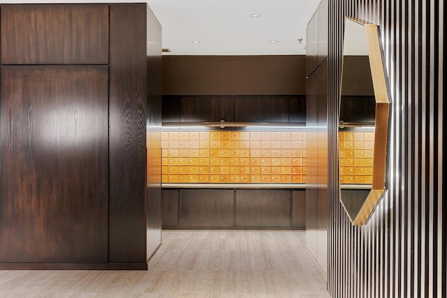 kitchen with dark brown cabinetry, light hardwood / wood-style flooring, and a mail area