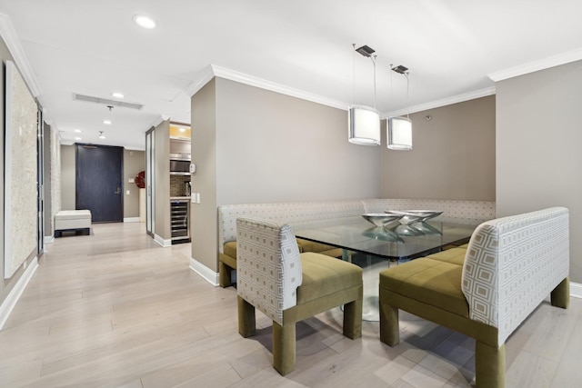 dining room featuring light hardwood / wood-style floors, ornamental molding, and beverage cooler