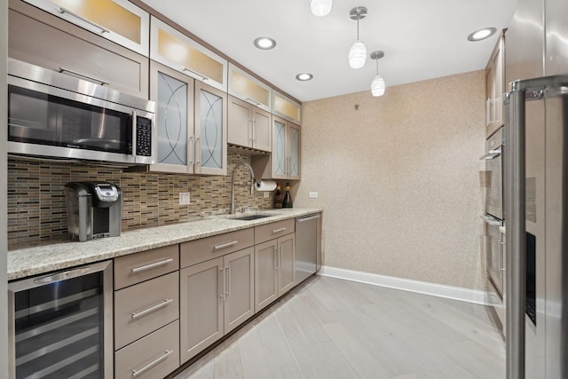 kitchen featuring wine cooler, sink, light stone counters, pendant lighting, and stainless steel appliances