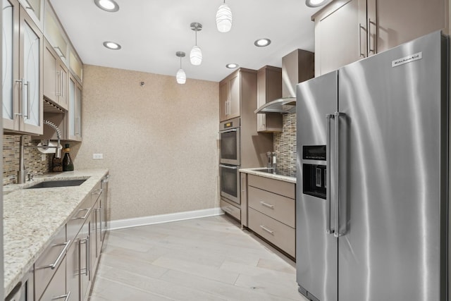 kitchen with pendant lighting, appliances with stainless steel finishes, wall chimney exhaust hood, and tasteful backsplash