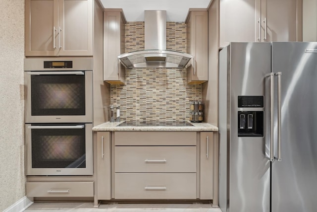 kitchen with tasteful backsplash, light stone countertops, wall chimney exhaust hood, and appliances with stainless steel finishes