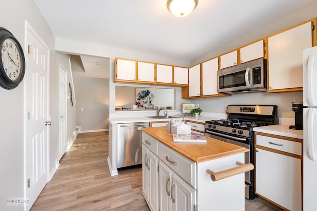 kitchen with sink, stainless steel appliances, white cabinetry, and a kitchen island