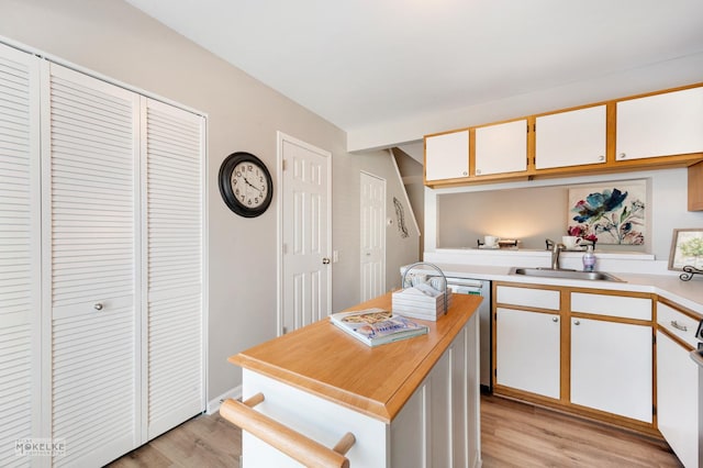 kitchen with sink, a kitchen island, white cabinets, and light hardwood / wood-style flooring