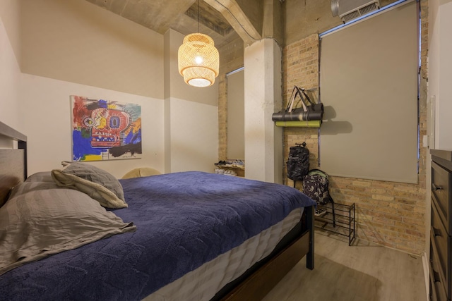 bedroom featuring brick wall and wood-type flooring