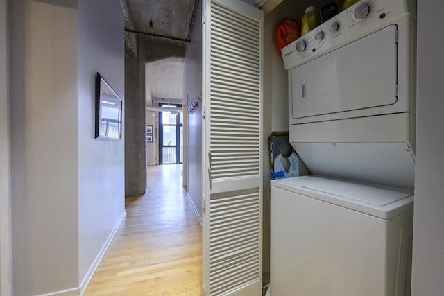 washroom with light hardwood / wood-style floors and stacked washer / dryer