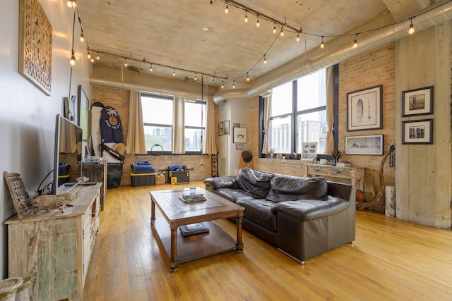 living room with brick wall and light hardwood / wood-style flooring