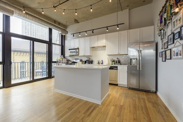 kitchen featuring stainless steel appliances, white cabinets, decorative backsplash, and light hardwood / wood-style flooring