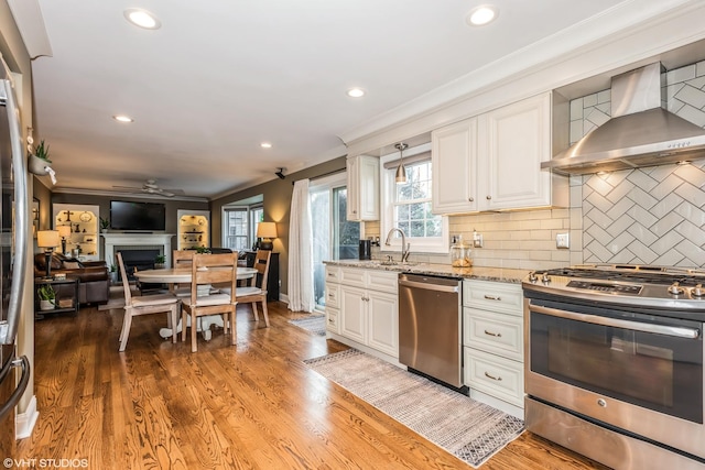 kitchen with white cabinetry, wall chimney exhaust hood, stainless steel appliances, and tasteful backsplash