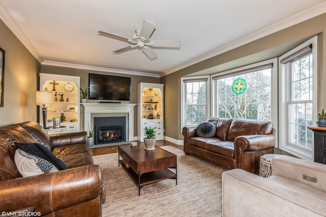 living room with a fireplace, light wood-type flooring, ceiling fan, and crown molding