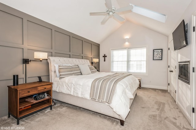 carpeted bedroom with vaulted ceiling with skylight and ceiling fan