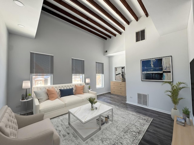 living room with a towering ceiling, beam ceiling, and dark hardwood / wood-style flooring