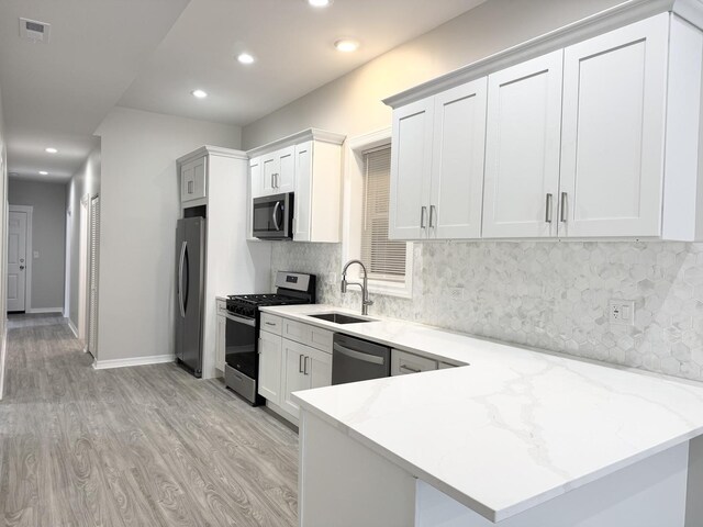 kitchen featuring kitchen peninsula, sink, white cabinetry, and appliances with stainless steel finishes