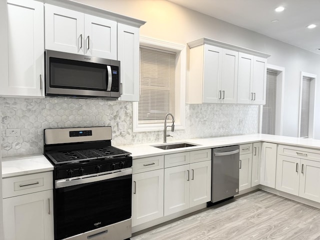 kitchen featuring light hardwood / wood-style floors, tasteful backsplash, sink, white cabinets, and stainless steel appliances