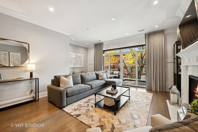 living room with a high end fireplace, crown molding, and hardwood / wood-style floors