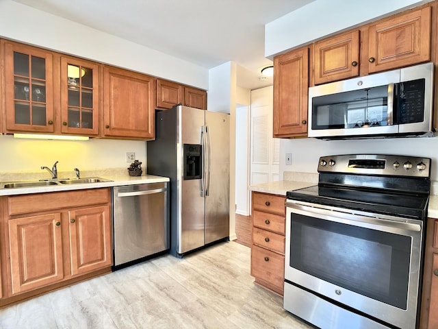 kitchen with appliances with stainless steel finishes, light hardwood / wood-style flooring, and sink