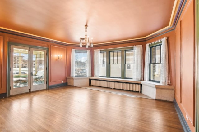 interior space featuring french doors, radiator heating unit, and an inviting chandelier