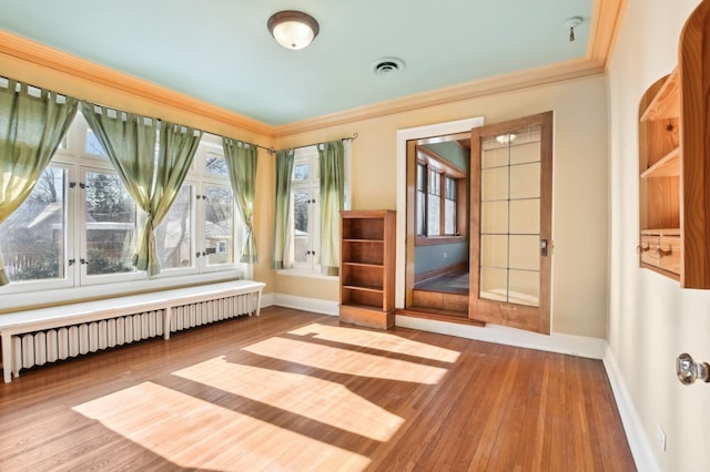 interior space featuring ornamental molding, radiator heating unit, and light hardwood / wood-style floors