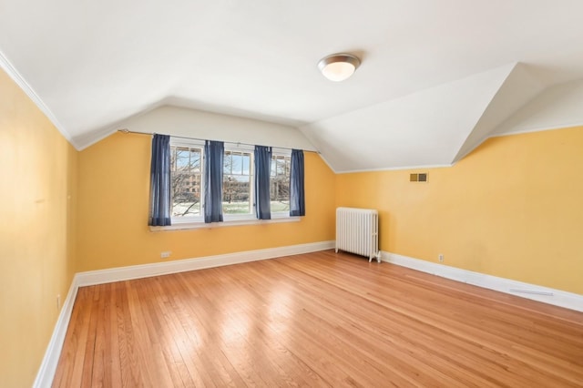 bonus room featuring wood-type flooring, lofted ceiling, and radiator