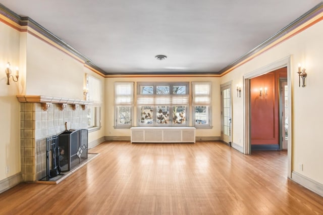 unfurnished living room featuring a wealth of natural light, radiator heating unit, and ornamental molding