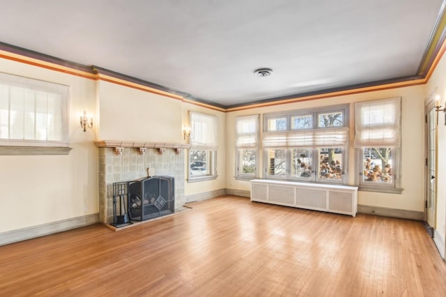 unfurnished living room with crown molding, radiator heating unit, light hardwood / wood-style floors, and a tile fireplace