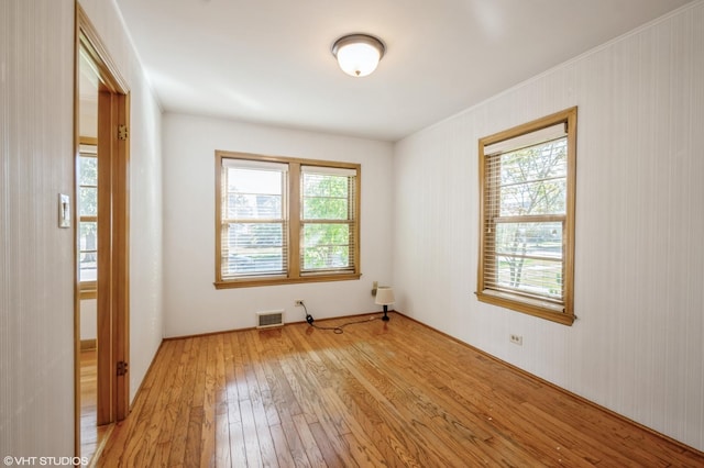 unfurnished room featuring light wood-type flooring and wooden walls