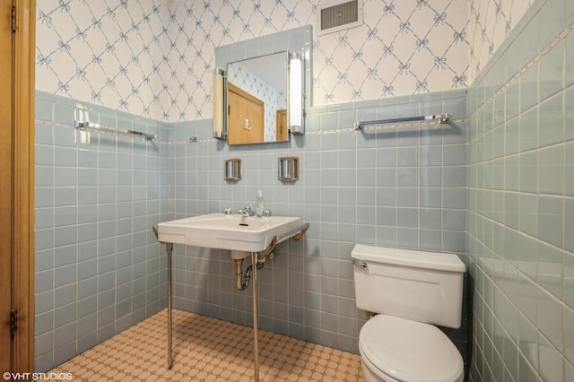 bathroom featuring tile walls, toilet, and sink