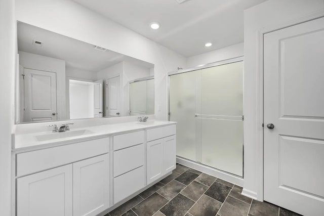 bathroom featuring a shower with shower door and vanity