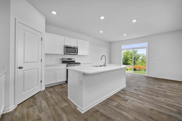 kitchen featuring appliances with stainless steel finishes, an island with sink, dark hardwood / wood-style floors, white cabinets, and sink