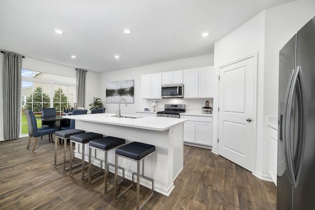 kitchen featuring a kitchen island with sink, appliances with stainless steel finishes, dark wood-type flooring, sink, and white cabinetry