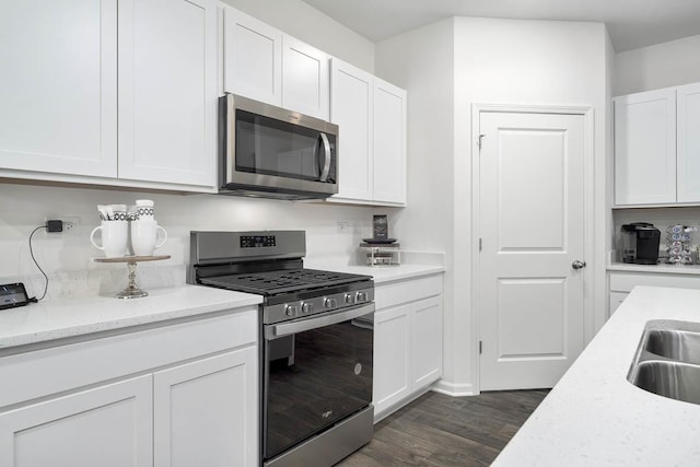 kitchen featuring dark hardwood / wood-style flooring, white cabinetry, light stone counters, and appliances with stainless steel finishes