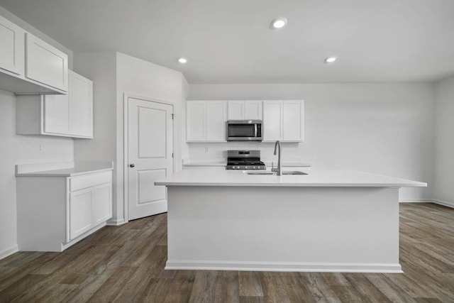 kitchen with sink, stainless steel appliances, white cabinetry, and a center island with sink