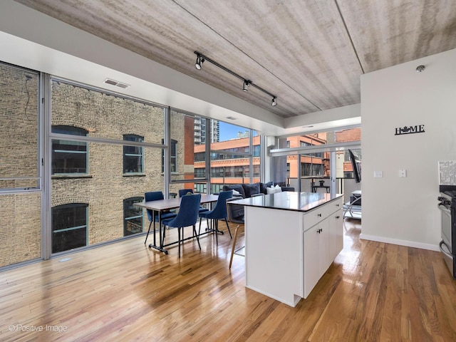 kitchen featuring white cabinets, a fireplace, light hardwood / wood-style flooring, a kitchen island, and rail lighting