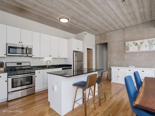 kitchen featuring appliances with stainless steel finishes, light hardwood / wood-style floors, a center island, white cabinets, and sink