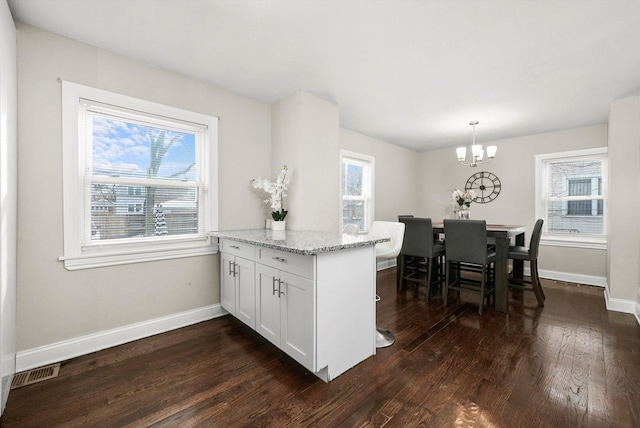 kitchen with white cabinetry, a wealth of natural light, hanging light fixtures, and light stone countertops