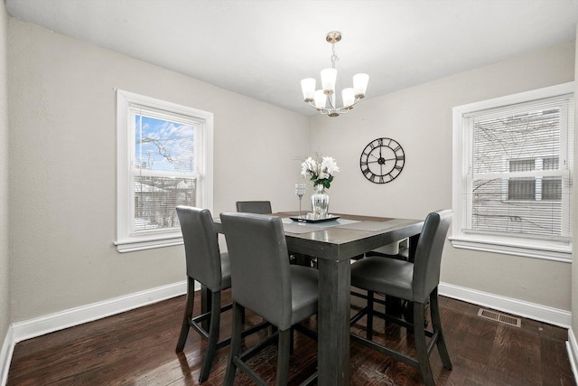 dining room with dark hardwood / wood-style flooring and an inviting chandelier