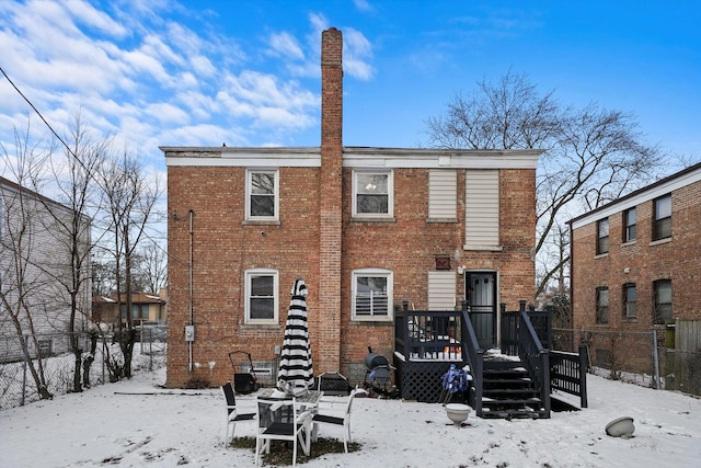 snow covered back of property with a wooden deck