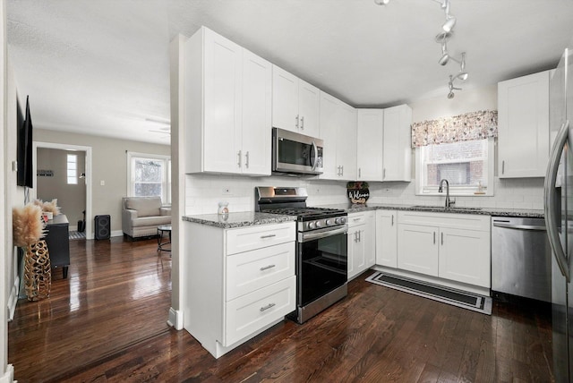 kitchen featuring stainless steel appliances, white cabinets, sink, and backsplash