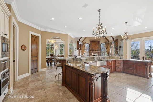 kitchen with an inviting chandelier, arched walkways, stainless steel appliances, and a healthy amount of sunlight