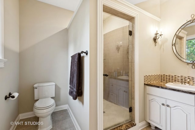 bathroom with a stall shower, vanity, tile patterned floors, baseboards, and toilet